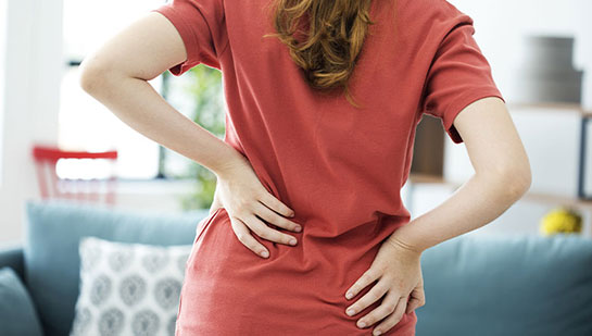 Woman holding lower back in pain before visiting Cleveland chiropractor
